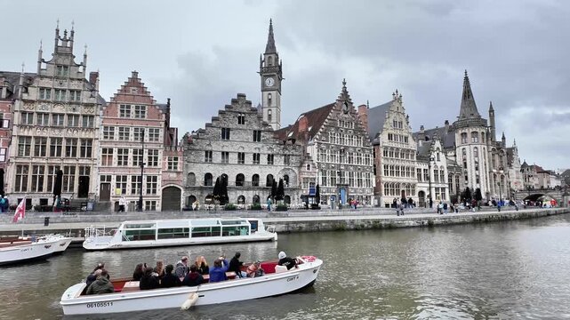 Panning shot of a scenic canal in Ghent with historic guild houses.
