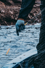 Fisherman wearing gloves carefully handling fishing net during maritime work © SIMANG