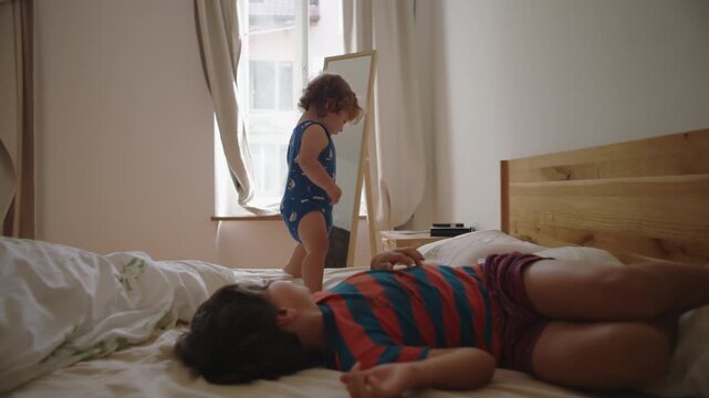 Young child and toddler jumping on bed together expressing excitement movement and playful chaos creating lively sibling bonding moment in everyday home setting