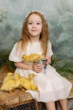 Cute girl holding tulips with ducklings, spring nature portrait with soft green background