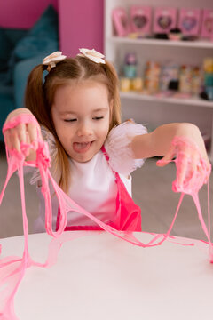 Little girl playing with pink slime indoors, creative sensory activity for children