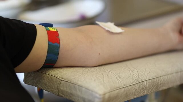 Blood donation concept. A donor gives blood. A close-up of a hand with a small blood bag attached during a blood donation. Donating blood for the military.