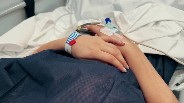 Close-up of an intravenous hospital in the hand of a patient lies on bed in the hospital. High quality 4k footage