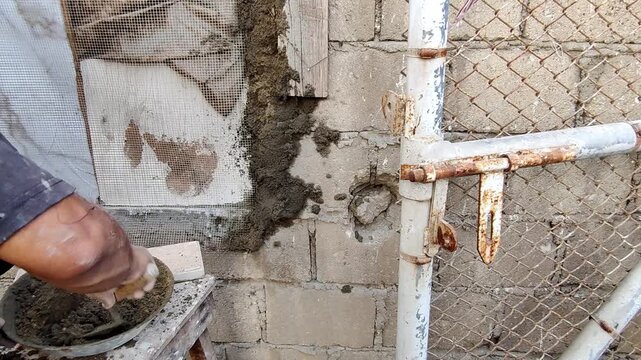 Worker throwing wet plaster onto wall to make it grip firmly