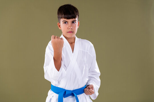 Young martial artist in white uniform performs a defensive stance with strong focus and correct alignment during training.