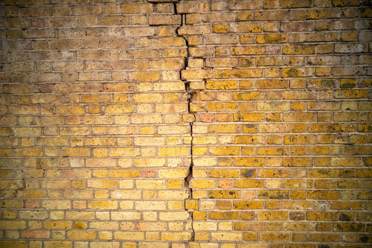 Weathered red British brick wall with dramatic crack texture background