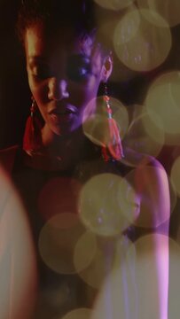 Vertical video: Musician pressing keys and singing on stage bokeh orbs drifting highlighting face