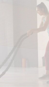 Vertical video: Woman gripping battle ropes, making waves for fitness, ramping then resting