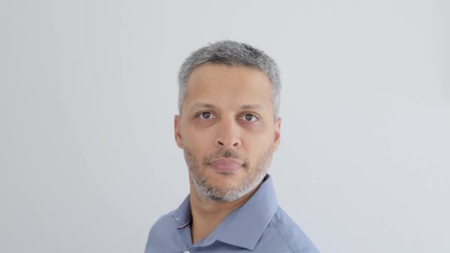 Mature man walks into frame waves with funny face and leaves against white background