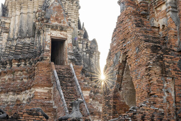 Obraz premium Majestic ancient ruin of Wat temple in Ayutthaya Thailand stands glowing under warm sunset light bringing peaceful serene feeling to visitors exploring old architecture built from aged red brick