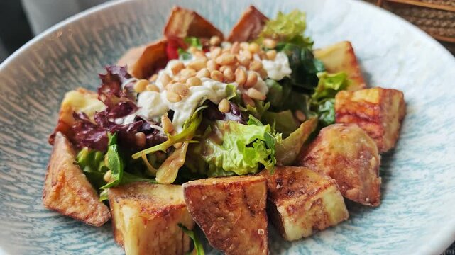 Grilled eggplant salad with greens and pine nuts in restaurant bowl