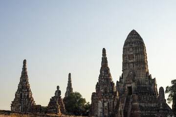 Obraz premium Majestic ancient temple ruins of Wat Ayutthaya in Thailand standing tall under peaceful clear blue sky evoking sense of tranquil historical awe and deep cultural reverence for past