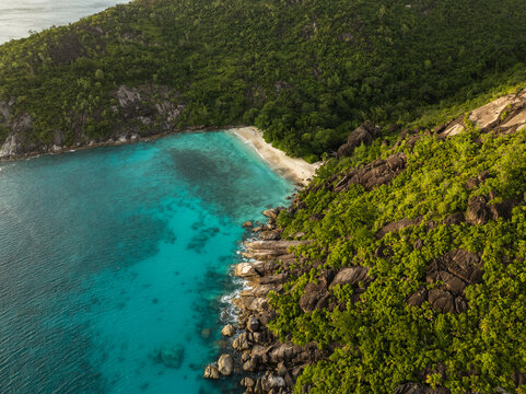 Aerial view of Cap Ternay bay with turquoise waters and lush tropical forest on the rocky hills in Cap Ternay, Port Glaud, Seychelles.