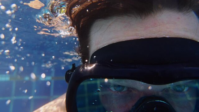Underwater Close Up Of Person Wearing Diving Mask With Floating Hair And Air Bubbles In Clear Blue Water, First Person Feeling And Exploration