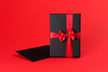 Fototapeta premium Gift Box With Red Ribbon and Card on a Red Background