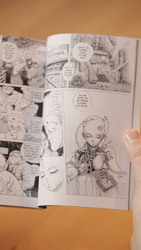 Over shoulder view while reading manga comic Orožne sanje (Gunnm) science fiction story in black-and-white drawings
