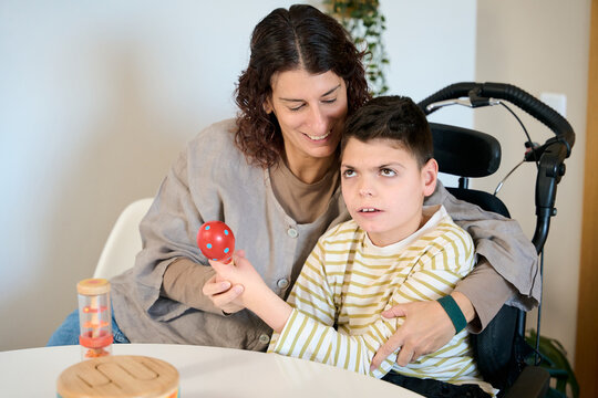 Mother helping son with cerebral palsy playing