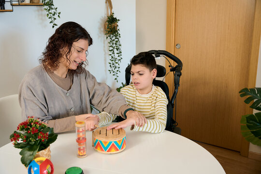 Woman helping boy with cerebral palsy during music therapy