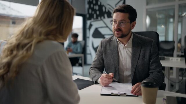 Caucasian leader of company businessman leading business interview writing notes talking with businesswoman candidate woman boss male review resume hiring job female intern two people talk in office