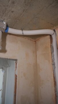 Cable installer routes flexible conduit up wall and across ceiling