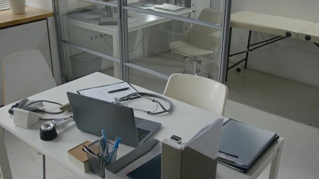 High angle shot of laptop resting on working desk of dermatologist cluttered with medical tools and documents at physicians office