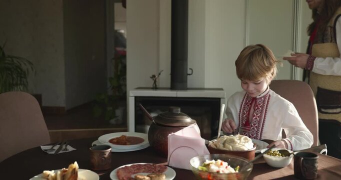Man With Kid Boy Eat Food Lunch Dinner. Family in Ukrainian Traditional Attire Childhood. 4K 10-bit