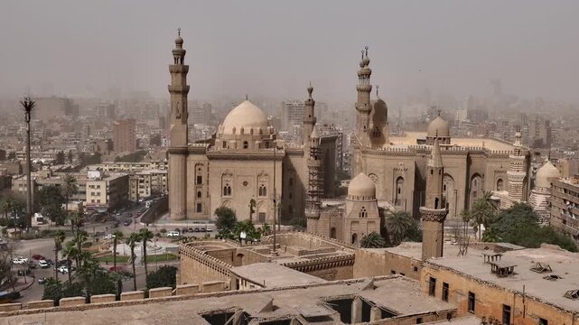 Historic mosques with tall minarets and grand domes dominate the hazy Cairo cityscape, Egypt, showcasing stunning Mamluk Islamic architecture from the medieval period.