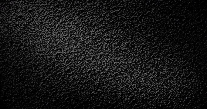 Abstract black texture. The slow, smooth diagonal movement of a dark, rough surface moving in a soft beam of light.