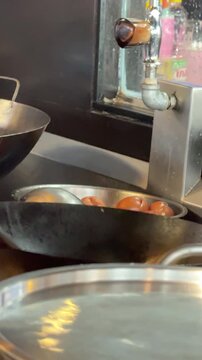 4K vertical footage of a professional chef stir-frying Pad See Ew (Flat Rice Noodles) in a large Chinese wok inside a commercial kitchen.