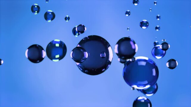 Various sizes of blue spheres, representing oil droplets or gel particles, float suspended in a blue liquid. The animation shows the spheres moving and merging, suitable for science visualizations, co