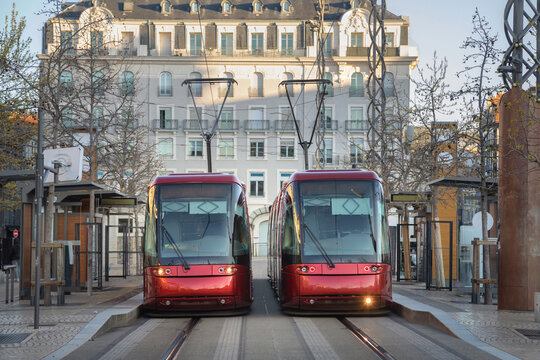Clermont-Ferrand, France - two red modern rubber-tyred trams staying on Place de Jaude tram station