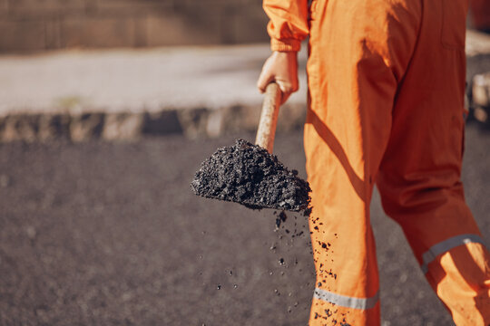 Construction worker working on a new asphalt layer on a public street.