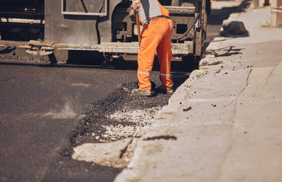 Construction workers working on a new asphalt layer on a public street.