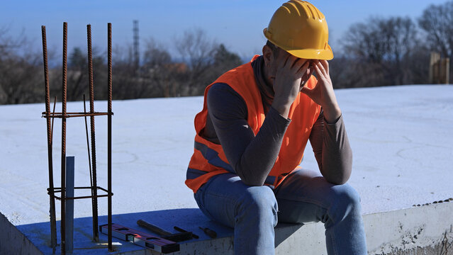Construction worker having a depressed period, headache, issues on a construction site outdoors.
