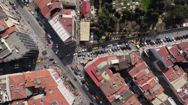 Top down aerial over bustling street and intersection in dense urban neighborhood of Istanbul, Turkey, daily life with cars, people, buildings