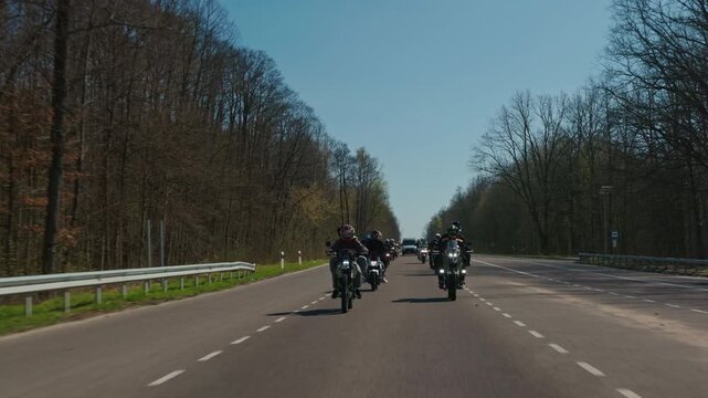 Steadicam slow motion tracking shot of a large motorcycle convoy riding through a forest road