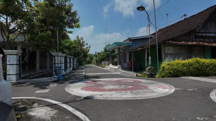 Naklejka premium Quiet residential street lined with traditional houses and lush greenery under a bright blue sky