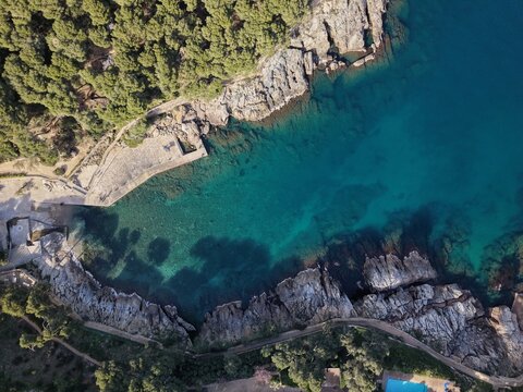 Top-down aerial view of rocky coastline and crystal clear turquoise water in Cala Aiguafreda, Begur.