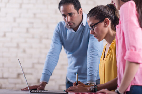 Middle Eastern startup team collaborating in a creative coworking office around a laptop and notes