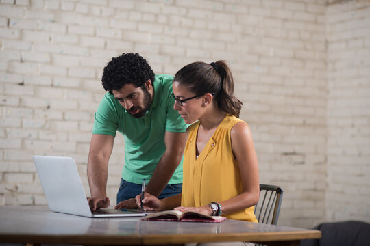 Young Middle Eastern coworkers collaborating on laptop and notebook in a creative startup office