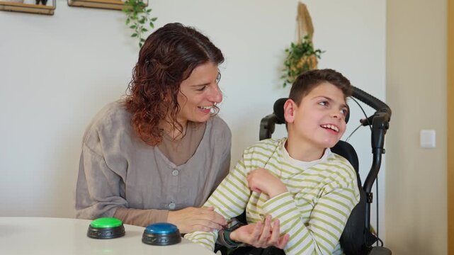 Mother assisting disabled son with communication buttons