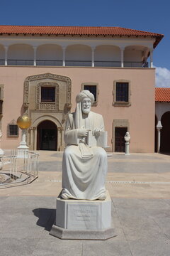 White marble statue of Ibn Gabirol, medieval Jewish philosopher and poet (1021&ndash;1058), seated in courtyard of Spanish colonial building with Moorish arches and terracotta roof under blue sky