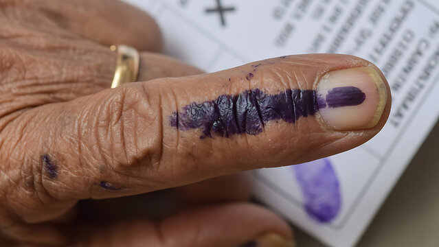 A close-up captures the act of voting, showing the indelible ink on a finger, symbolizing civic participation and the right to choose. 