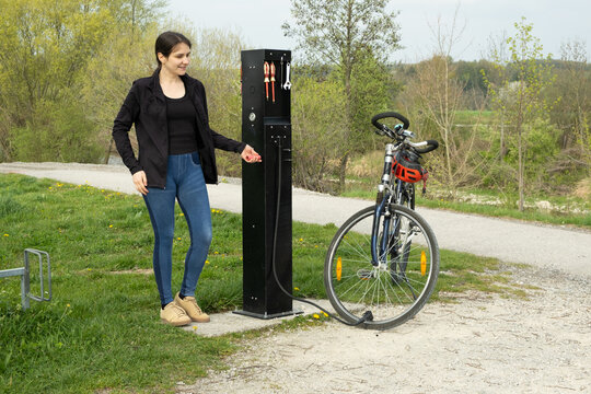 Woman inflating a bicycle tire using a manual pump station.