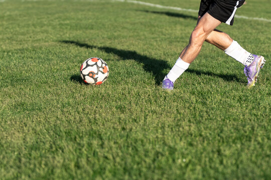 Soccer Player Approaching Ball on Grass Field with Shadow