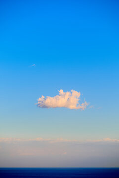 Tranquil seascape with a fluffy cloud floating above the blue sea