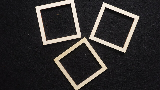 Three wooden square frames on a dark background