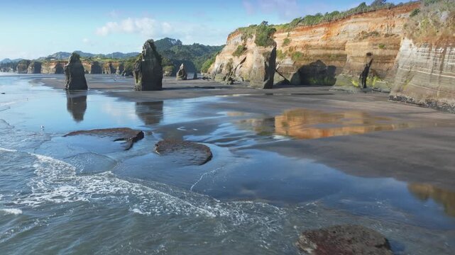 The stunning geological formations of the Three Sisters at Tongaporutu Beach, Taranaki, New Zealand, are sculpted by the Tasman Sea. This coastal landscape showcases layered cliffs and sea stacks
