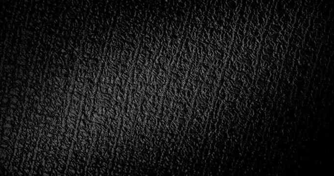 Abstract black texture. The slow, smooth diagonal movement of a dark, rough surface moving in a soft beam of light.