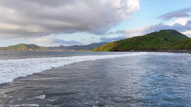 Aerial of waves approaching a black sand beach in Bali Indonesia.